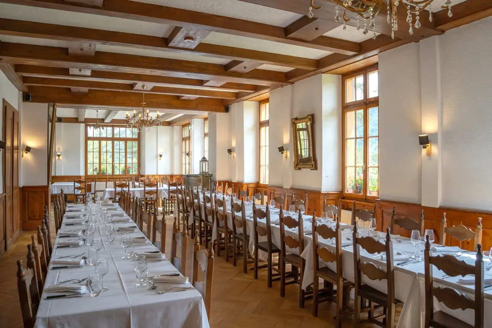 La salle historique de L'Honorine dressée, longues tables nappées de blanc et poutres d'époque — Grand Hôtel & Kurhaus Arolla