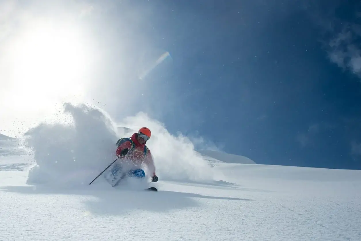 A freeride skier raising a cloud of powder above Arolla