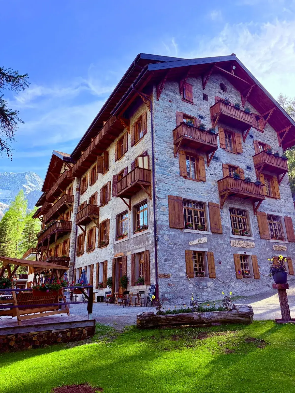 Stone façade of the Grand Hôtel & Kurhaus in summer, flower-filled wooden balconies — Arolla, Val d'Hérens