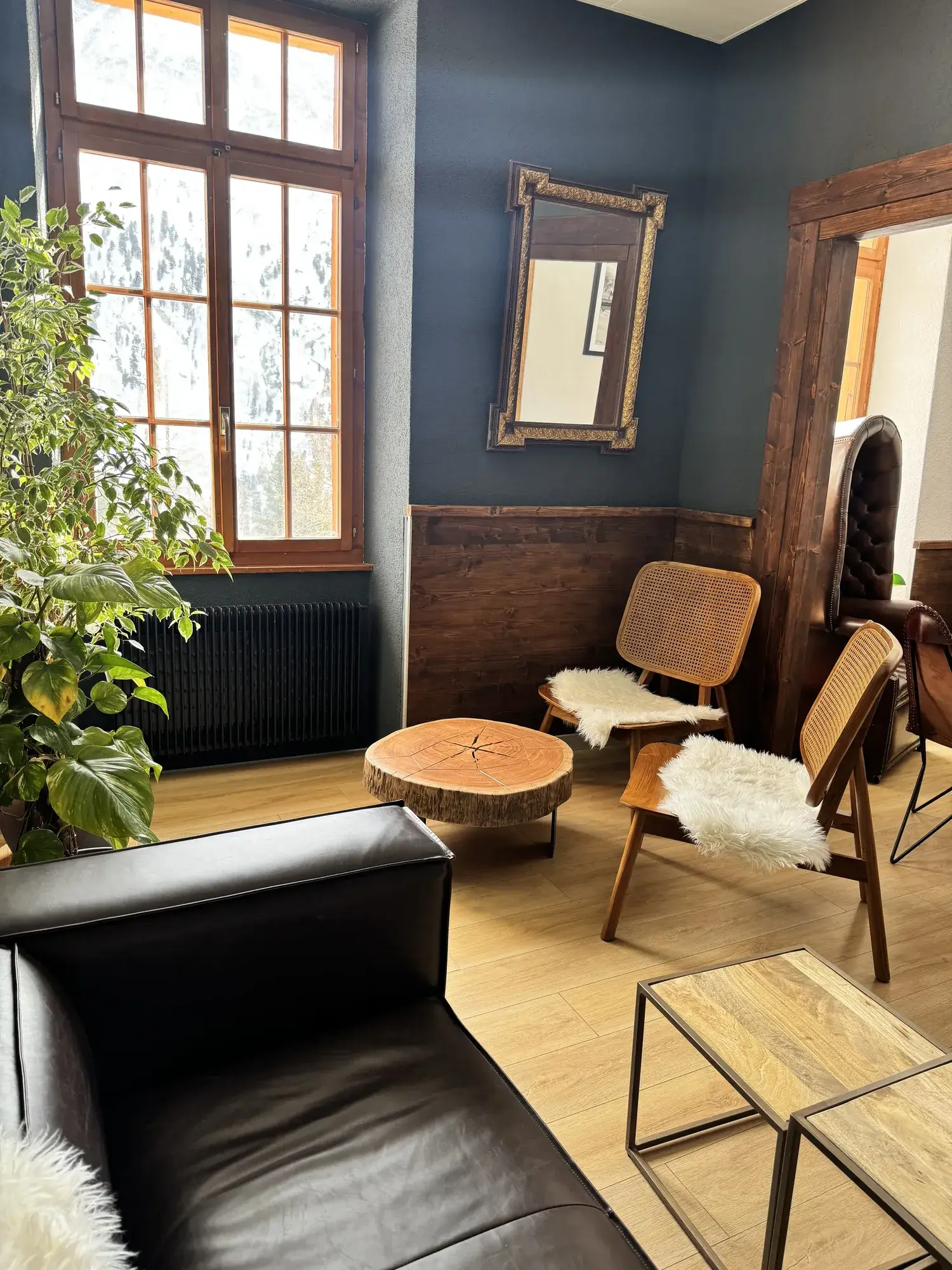 Le petit salon aux murs bleu nuit, fauteuils cannés et table en rondin