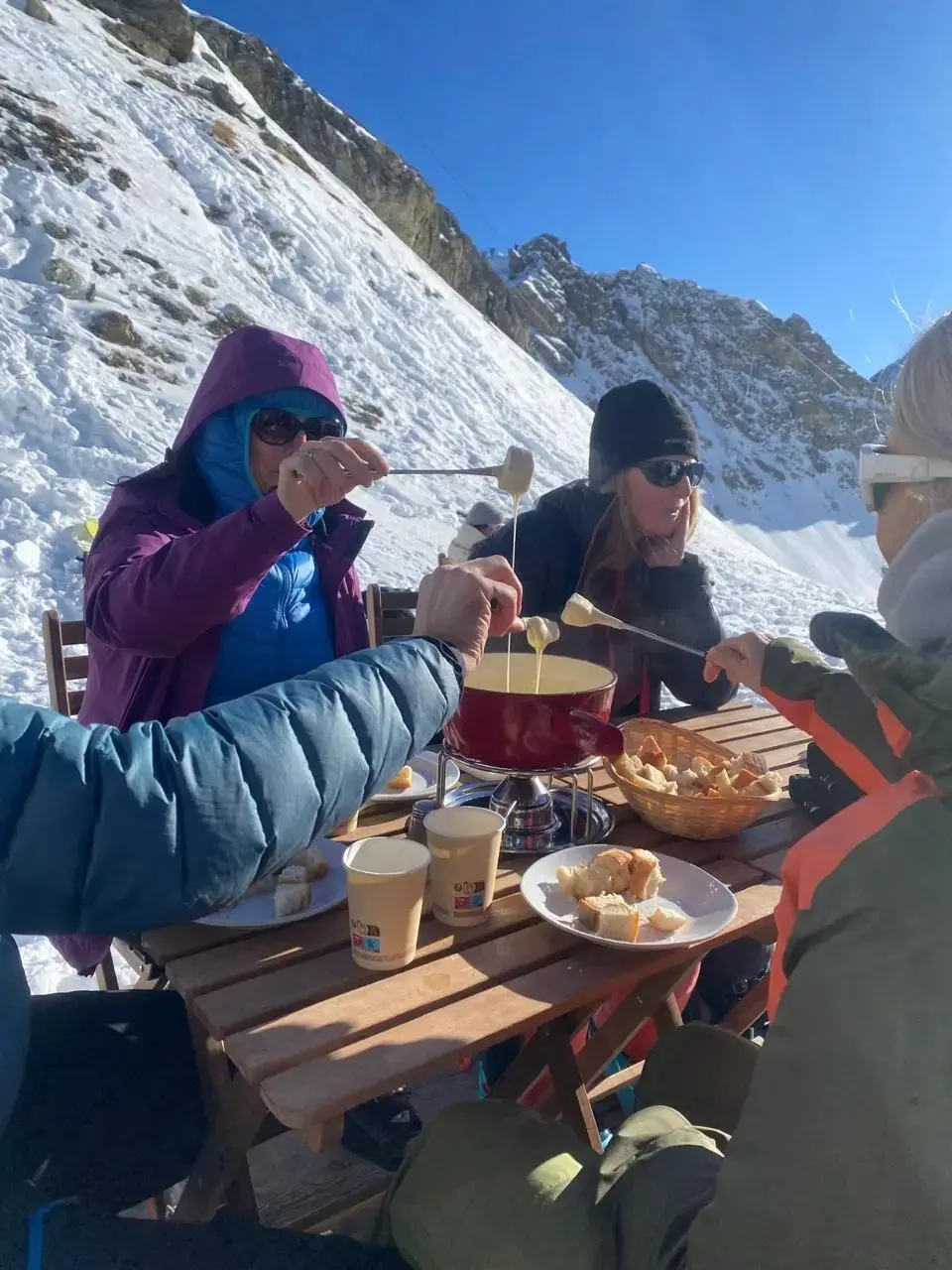 Fondue au fromage partagée en tenue de ski sur la terrasse de La Chotte — Arolla, 2 166 m